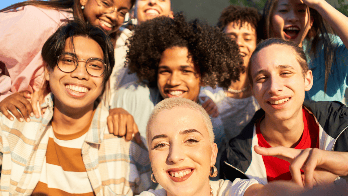 A diverse group of happy fans taking a selfie outdoors, representing creator audience engagement and community connection in 2025.