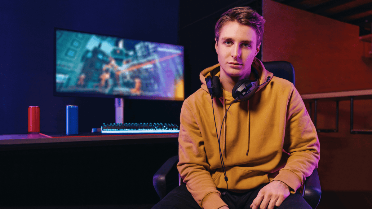 A digital content creator sitting in front of a gaming-style workstation with a monitor and headphones, representing modern creators using push notification marketing tools to engage their audience.