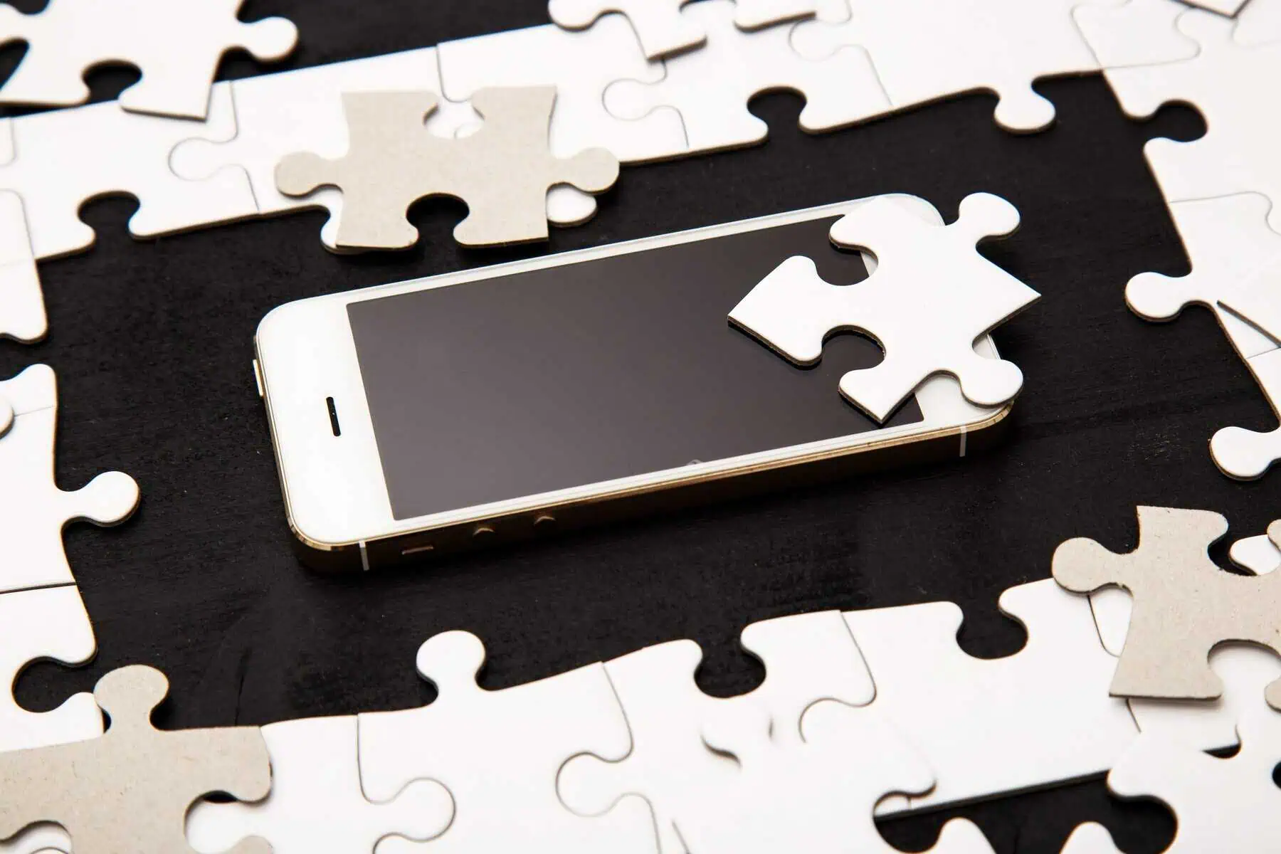 Smartphone surrounded by puzzle pieces, representing how a digital loyalty card platform fits into a wider loyalty infrastructure