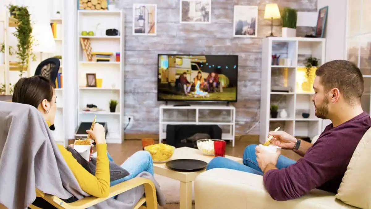 Couple watching TV at home in a relaxed setting, illustrating how TV viewing creates passive attention rather than immediate purchase intent