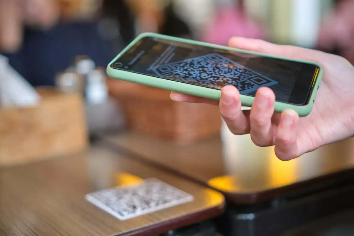 Customer scanning a QR code on a shop counter to join a loyalty program for small business